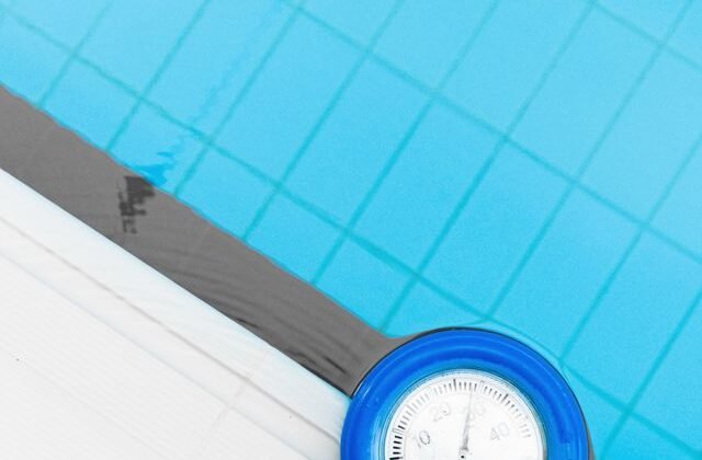 Floating thermometer measuring cold water temperature in a blue pool